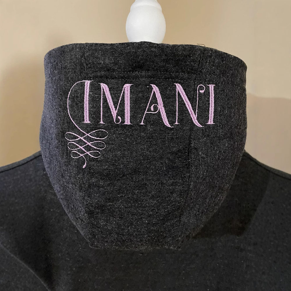 The hoodie has pink embroidered print details